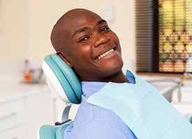 man smiling in green exam chair