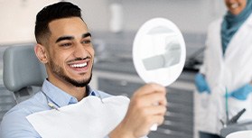 Man smiling at reflection in mirror in treatment chair