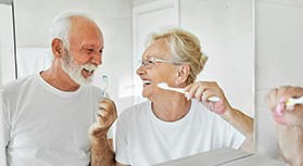 Senior couple smiling while brushing their teeth