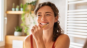 Woman smiling while brushing her teeth