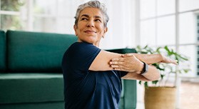 Senior woman smiling while stretching at home