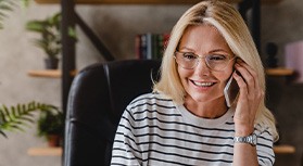 Woman with glasses smiling while talking on phone