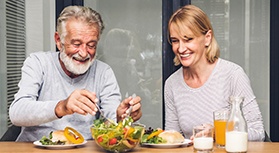 Man with white hair and blond woman having healthy meal together