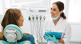 Dentist smiling while taking notes on clipboard