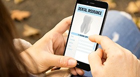 Patient looking at dental insurance form on phone outside