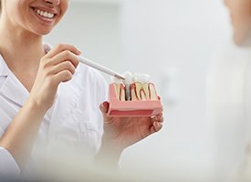 dentist showing a patient a model of how dental implants work