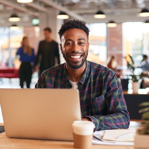 Man smiling while working in office on laptop