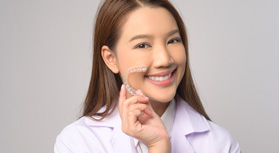 Woman smiling while holding clear aligner