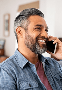 Man in blue shirt smiling while talking on phone