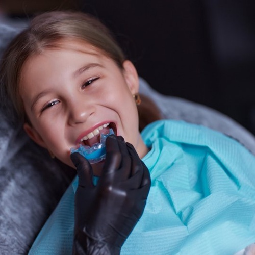  Girl opening her mouth as dentist places a clear aligner