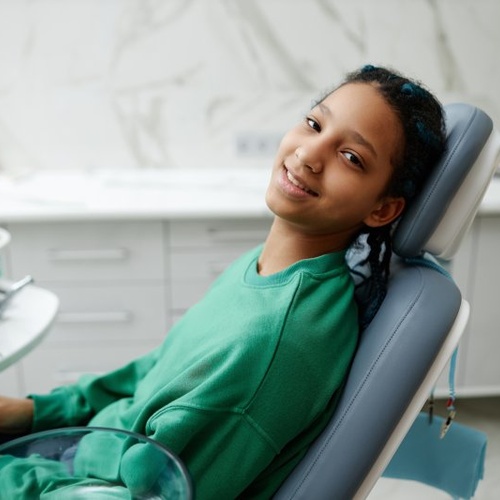 Teenage smiling in patient’s chair at the dentist