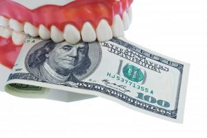 A dental model holding a dollar bill.