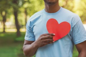 a person holding a paper cutout of a heart up to their chest