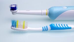 A manual and electric toothbrush lying next to each other