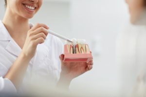 female dentist holding dental implants model 