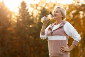 sporty mature woman drinking water bottle outdoors 