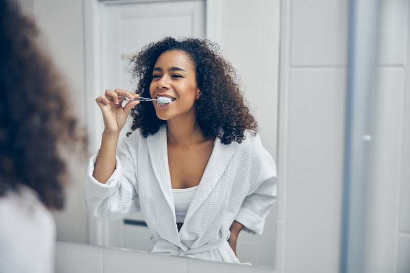 woman brushing teeth in bathroom