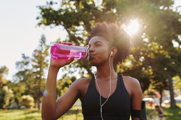 Woman drinking from her refillable water bottle during the summertime.