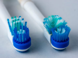 a brand-new toothbrush next to an old, frayed toothbrush