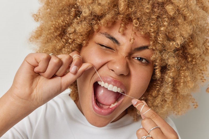 a woman flossing after visiting a dentist in Canton