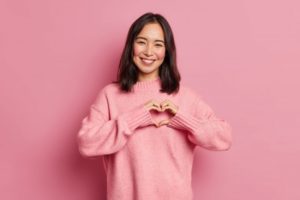 a woman smiling and forming a heart with her hands