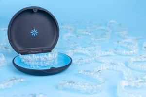 Invisalign container surrounded by aligner trays on a blue surface