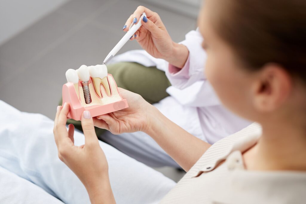 Dentist pointing to sample dental implant held by patient