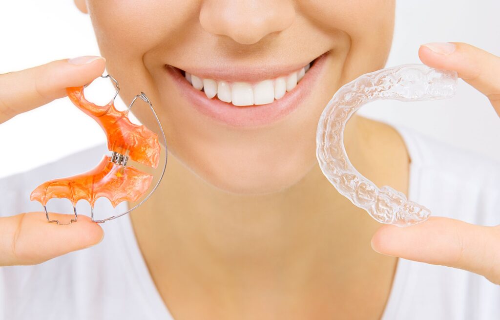Woman holding retainer and clear aligner
