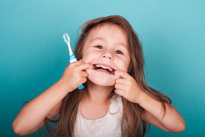 Child makes silly face holding toothbrush