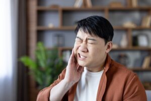 Man holding face wincing in pain.